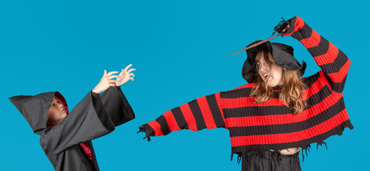 Halloween Theme. Young witch girl in striped sweater and black hat holding magic stick and making...
