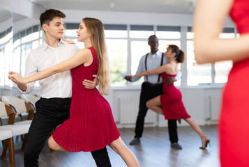 Happy woman enjoying impassioned merengue with male partner in latin dance room during party....