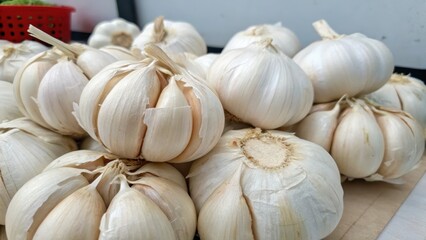 Fresh Garlic Bulbs Piled on a Wooden Surface in Bright Lighting