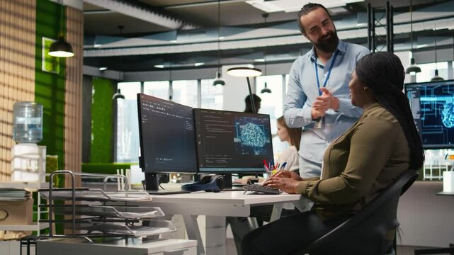 Pleased startup office manager applauding female programmer for optimizing code using AI. Satisfied team leader offering positive feedback to work done by IT specialist in office, camera A