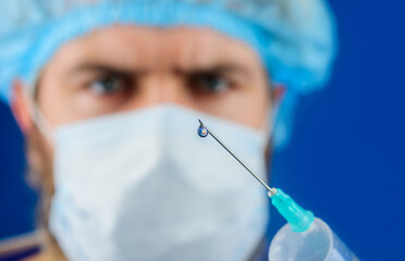 Vaccination. Closeup drop of medicine, liquid medication or drug on tip of syringe needle for...