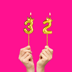 Birthday on a fuchsia background with the number 32 - Hands holding number-shaped candles