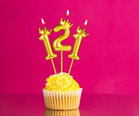 Birthday celebration with number 121 candle - Yellow cupcake on a pink background