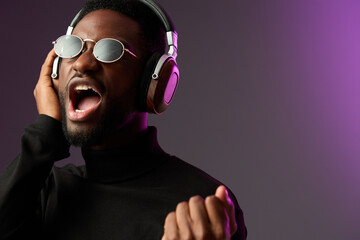 Young Black man singing passionately with headphones, wearing sunglasses and black turtleneck,...