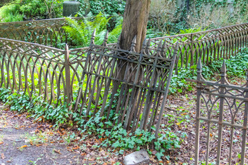 Decorative metal fence with curved design separating green garden area from urban walkway