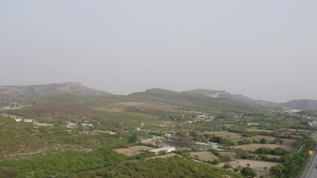 Expansive view of green hills, scattered farms, and rural settlements near Kallar Kahar. Punjab, Pakistan