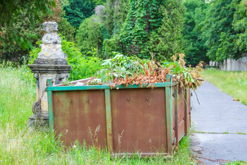 Weathered concrete cemetery structure with green metal roof standing prominently against lush summer foliage in memorial garden setting