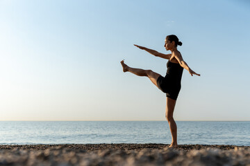 Obraz premium Focused yoga balance pose at sunrise by the peaceful sea