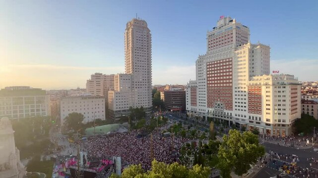 Elevated view of a large crowd gathering in Plaza de Espa&ntilde;a, Madrid, with the iconic Torre de Madrid and Edificio Espa&ntilde;a dominating the skyline during a sunny day