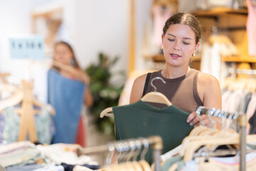 Young woman is shopping in womens clothing department, buying short sleeve shirt. Off line clothing...
