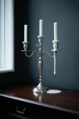 Elegant Silver Candelabra with White Candles and Melted Wax Accent in Soft Ambient Light