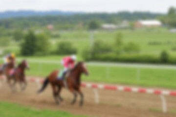 Obraz premium blurry racetrack, showing horses racing on a track with riders on them, blurry wallpaper.