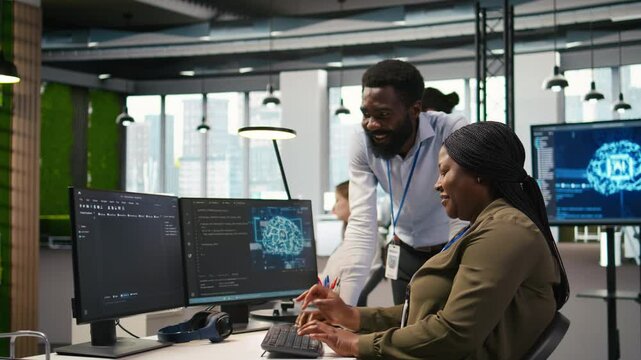 Happy engineers enjoying funny conversation at desk while using AI on computer to optimize performance. Cheerful colleagues in office chatting, training deep learning models using PC, camera A