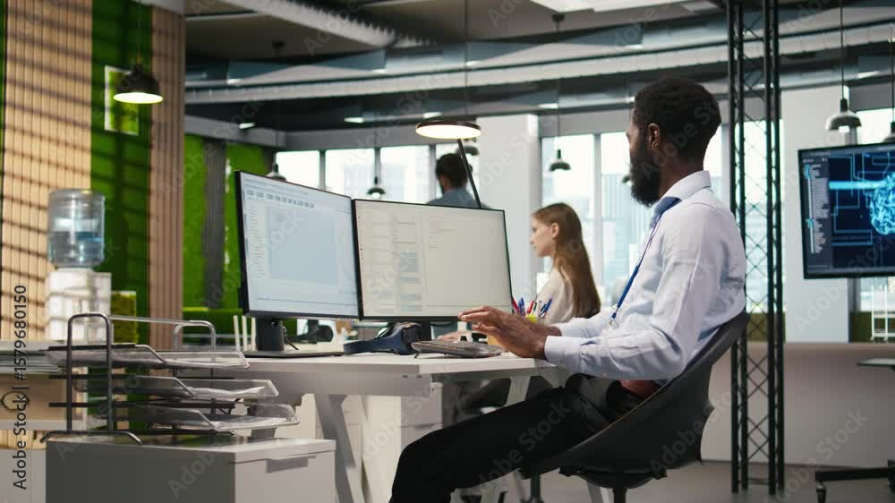 Poster admin in tech startup office using pc, compiling software patches to fix bugs, troubleshooting backe