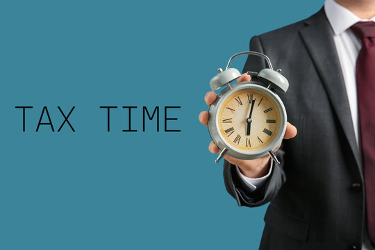 Businessman holding alarm clock on color background. Time management concept