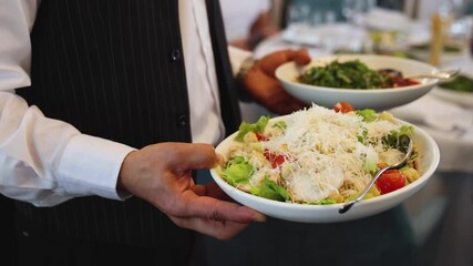 Waiter in uniform serving dishes on party event, server carrying plates with food at the table, catering service on wedding reception, cafe restaurant table service, waiters arranging dinner banquet