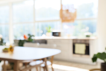Blurred view of light kitchen with dining table and counters