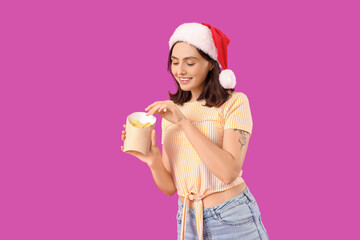 Young woman in Santa hat with french fries on purple background