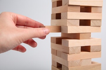 Lviv, Ukraine - December 04, 2023: Woman playing Jenga on light gray background, closeup
