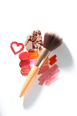 Different cosmetic products and makeup brush on white background, flat lay