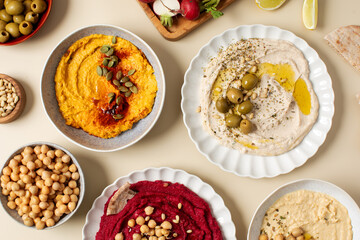  Different types of hummus in bowls and plates. Beetroot, pumpkin, chickpea and bean hummus. 