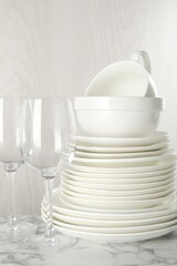 Different clean dishware on white marble table indoors, closeup