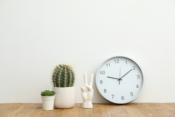 Different decor and round clock on wooden table near white wall indoors