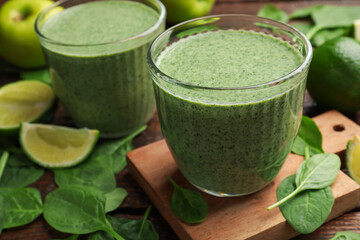 Tasty spinach smoothie and ingredients on wooden table, closeup