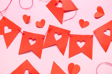 Garland made of red paper flags with hearts on pink background. Valentine's Day celebration