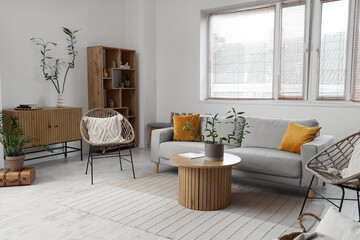 Stylish interior of living room with bamboo stems on coffee table and sofa