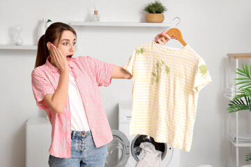 Shocked young woman with dirty t-shirt in laundry room