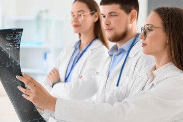 Young doctors studying x-ray image of spine at hospital, closeup