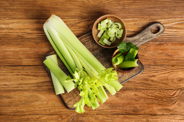 Board and bowls with fresh green celery on wooden background