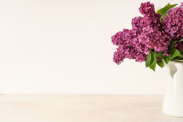 Jug with blooming lilac flowers on white background