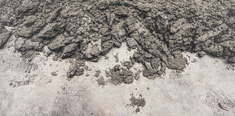 Close-up of rough, wet cement texture with uneven surfaces, showing its granular composition.