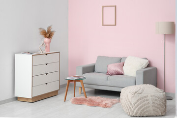 Cozy sofa, chest of drawers, coffee table and pouf in living room