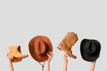 Female hands with stylish cowboy hats and shoes on grey background