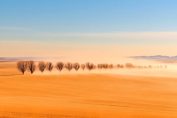 Obraz premium A serene landscape with a row of bare trees silhouetted against a warm pastel sky their forms slowly dissolving into the distant hazy horizon