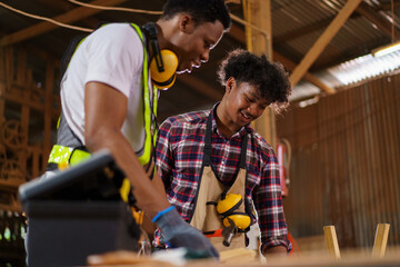 Two professional African carpenters are working together in sawmill or workshop.