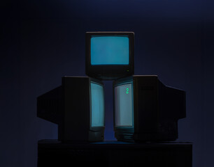 vintage televisions turned on with glowing screens on dark background