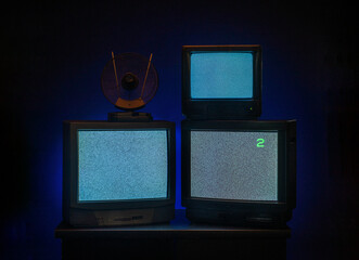 vintage televisions turned on with glowing screens on dark background