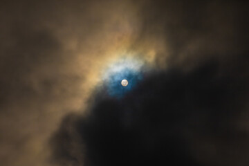 Sun shines through high clouds and creates dramatically brilliant multicolored halo 