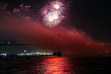 Drone flight through holiday fireworks above water with reflection on the black sky background