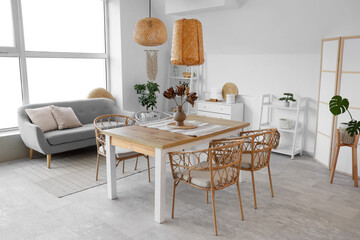 Interior of light dining room with table, sofa and shelf units
