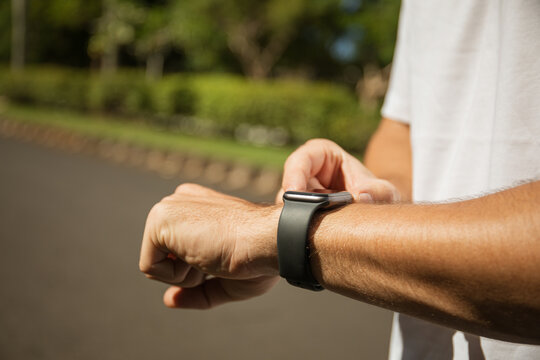 Individual interacting with smartwatch on wrist while outdoors - Powered by Adobe