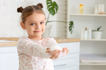 Little girl with soap bar washing her hands in bathroom