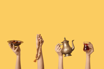 Female hands with Turkish tea, prayer beads and dates on yellow background