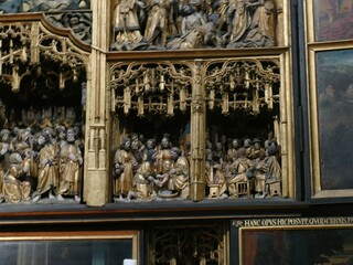 Gilded wooden altarpiece revealing biblical narratives through ornate golden carvings, representing...