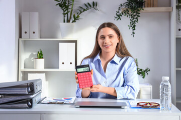 Female accountant with calculator at desk in office
