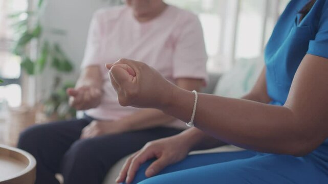 Asian health care worker giving elderly woman physiotherapy at home, home nurse, home care service concept
